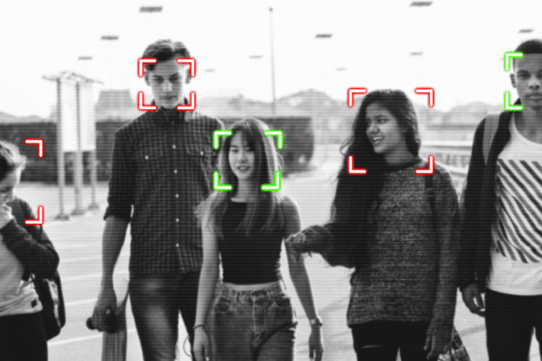 Black and white image of people walking toward the camera with their faces appearing to be tracked by facial recognition technology