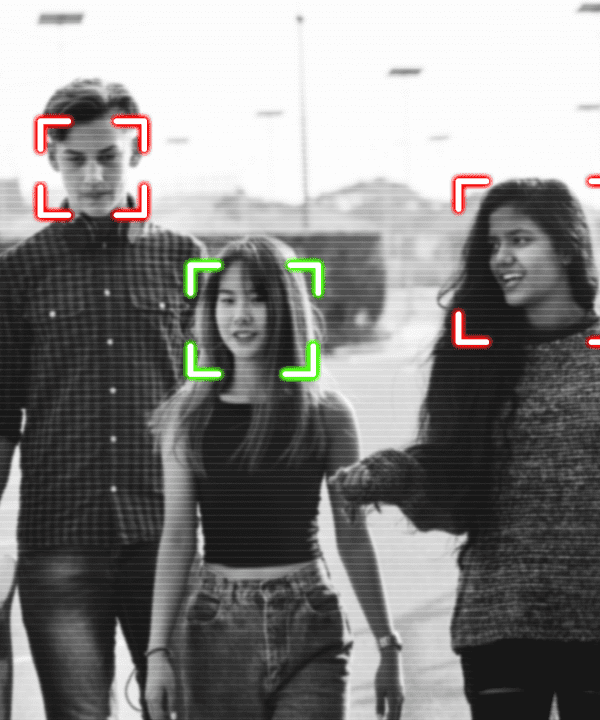 Black and white image of people walking toward the camera with their faces appearing to be tracked by facial recognition technology
