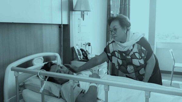 Worried mother taking care of a son with lying in hospital bed.