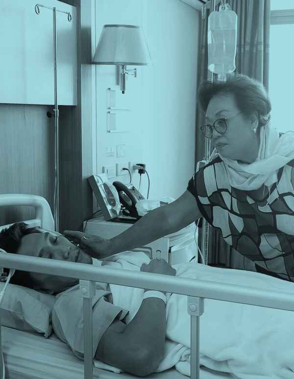 Worried mother taking care of a son with lying in hospital bed.