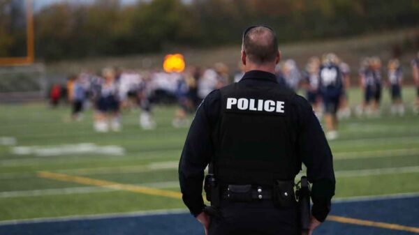 Back of a Police Officer overlooking what appears to be an out of focus football field.