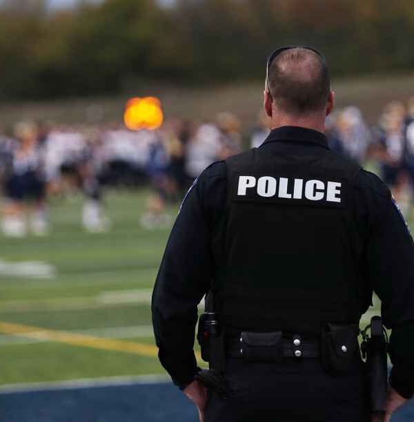 Back of a Police Officer overlooking what appears to be an out of focus football field.