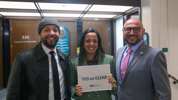 Jeff, Nalini and Eddie in the San Diego County Administrative Building. Nalini is holding a "Yes on CLEAR" sign.
