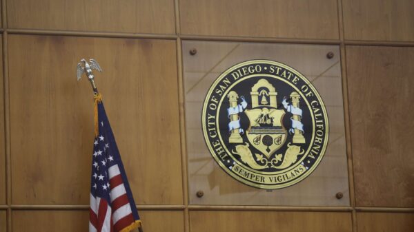 Photo of City of San Diego seal in the city council chambers. An American flag is in the left bottom corner.