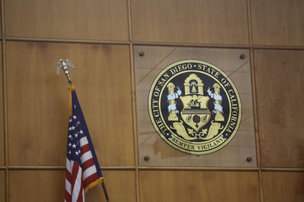 Photo of City of San Diego seal in the city council chambers. An American flag is in the left bottom corner.