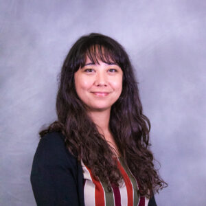 Photo of Samantha smiling at the camera in front of a gray background.