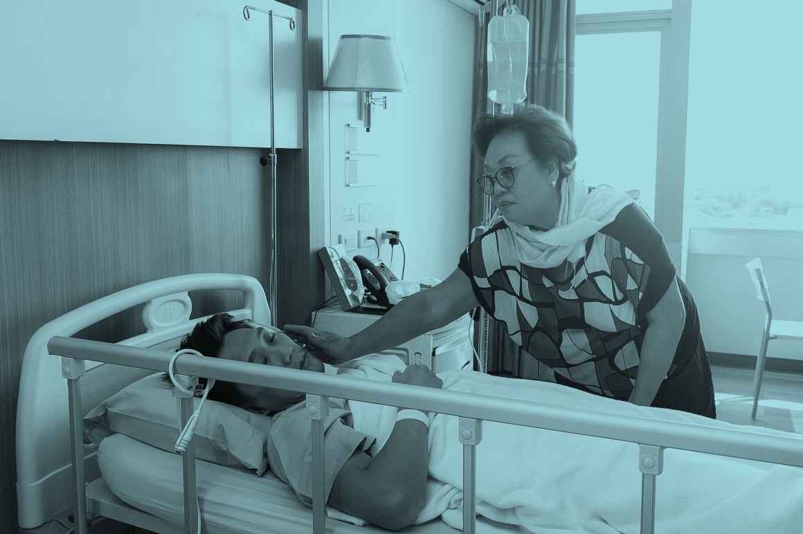 Worried mother taking care of a son with lying in hospital bed.