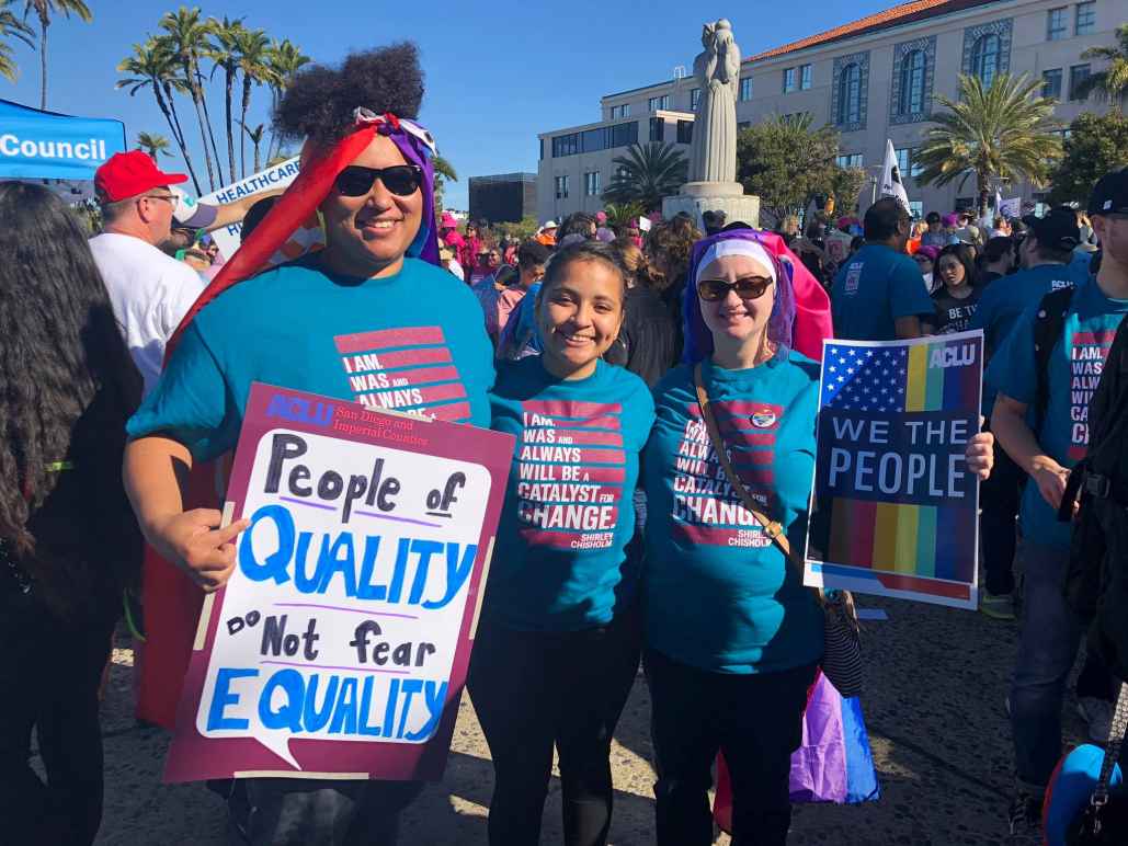 Three people posing for a photo with their posters for the Women's March 2019.