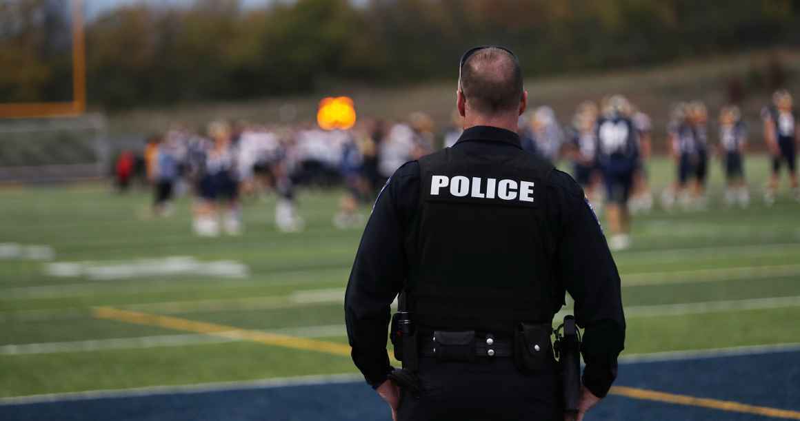 Back of a Police Officer overlooking what appears to be an out of focus football field.