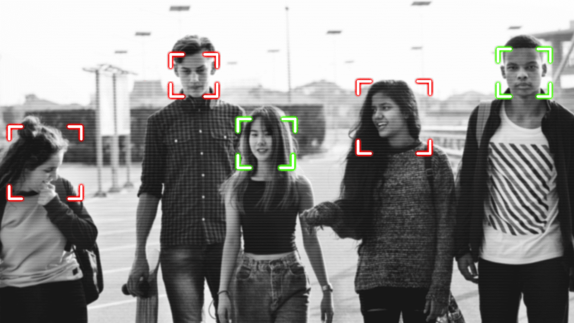 Black and white image of people walking toward the camera with their faces appearing to be tracked by facial recognition technology