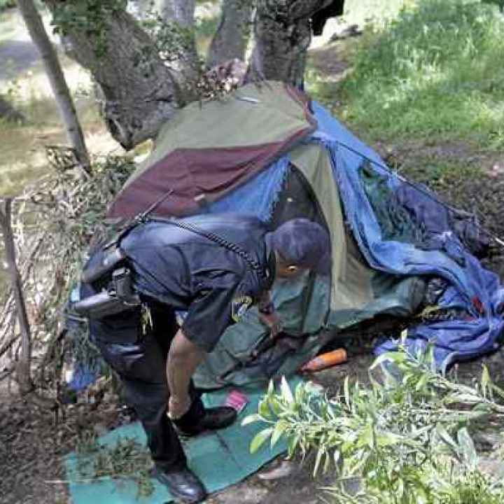 An Open Letter to California Officials: Housing First A police officer peers into a tent that may have been part of an encampment for people experiencing homelessness.